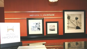 Un área de recepción con un cartel que dice 'Welcome to Richfield', cuadros enmarcados en la pared y un cartel de 'Hilton Honors'.