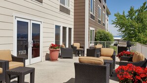 A patio area with wicker furniture, potted plants, and a grill.