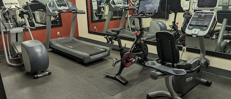 A gym with treadmills, stationary bikes, and an elliptical machine.