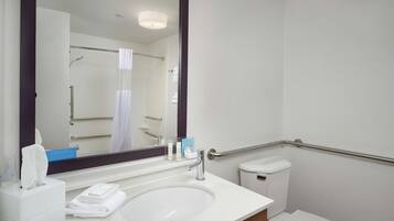 A bathroom with a white sink, a mirror, a towel dispenser, and a toilet.