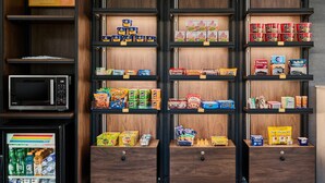 A vending machine and shelves stocked with snacks and beverages.