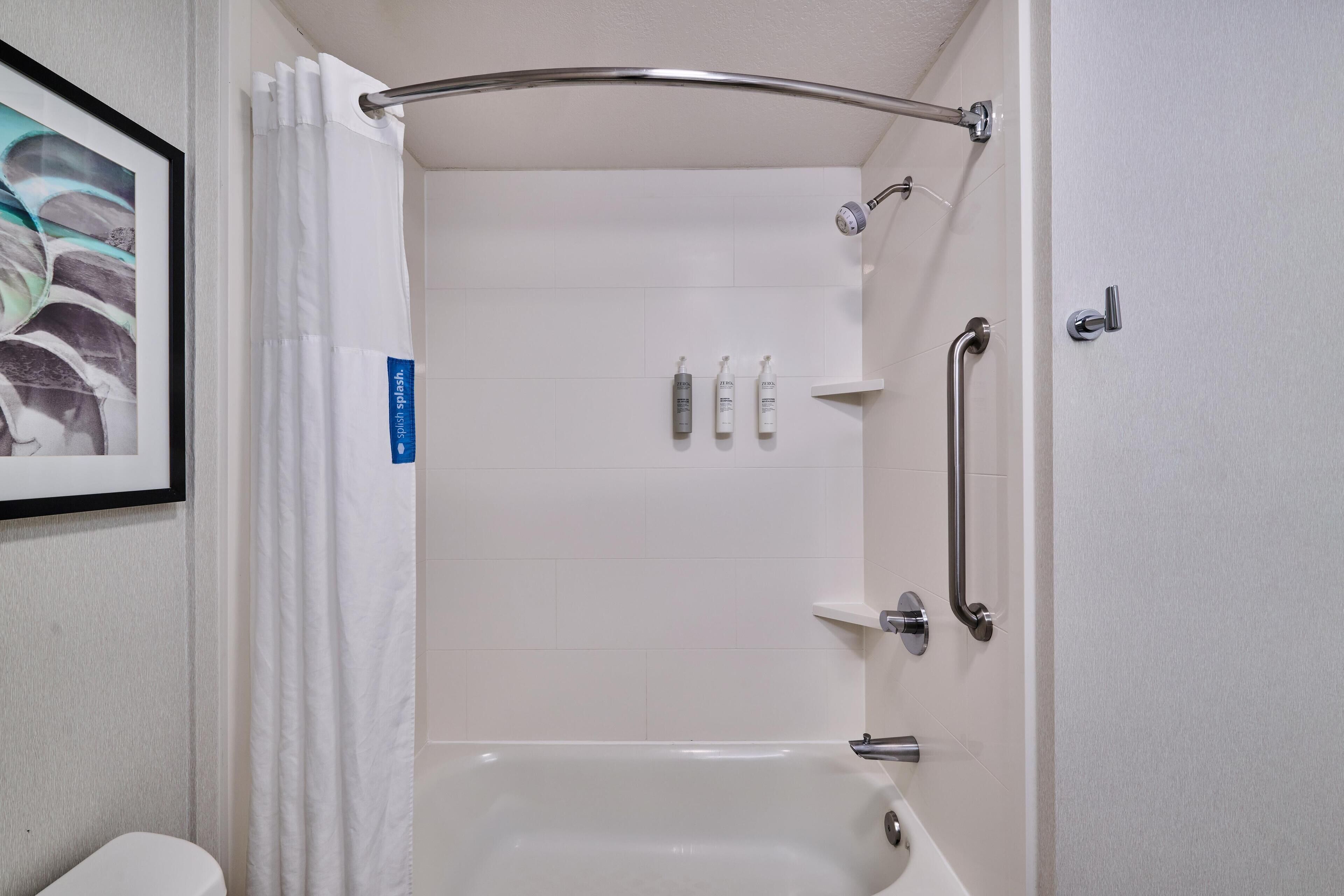 Ein modernes Badezimmer mit Dusche, Toilette und einem gerahmten Bild an der Wand.