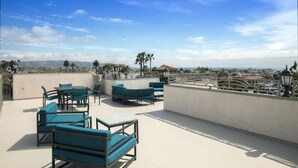 A rooftop terrace with outdoor seating, a railing, and a view of the cityscape.