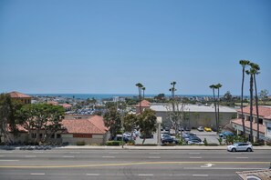 A coastal town with clear skies, a parking lot, and buildings with red-tiled roofs.