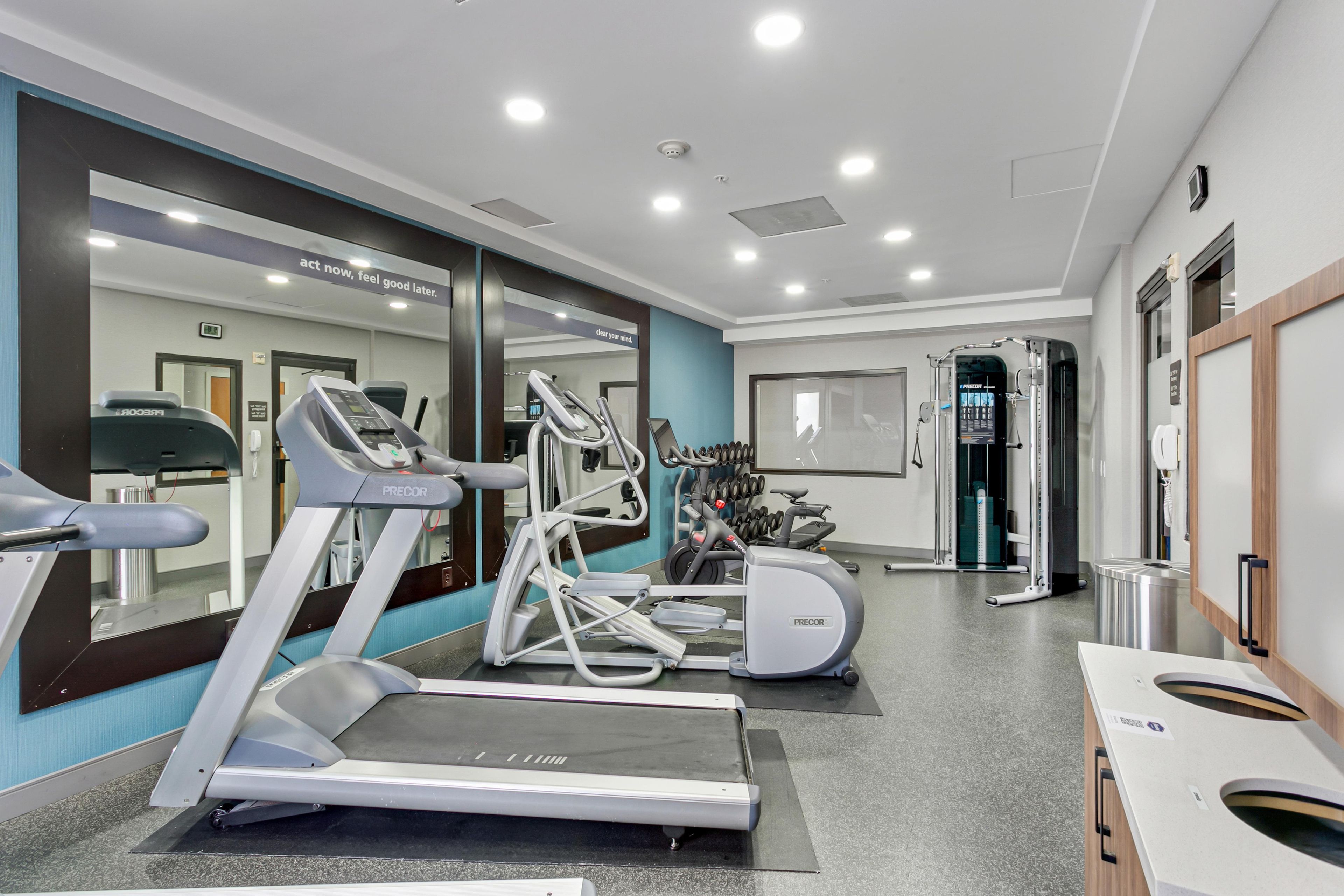 A modern gym with treadmills, elliptical machines, and free weights.