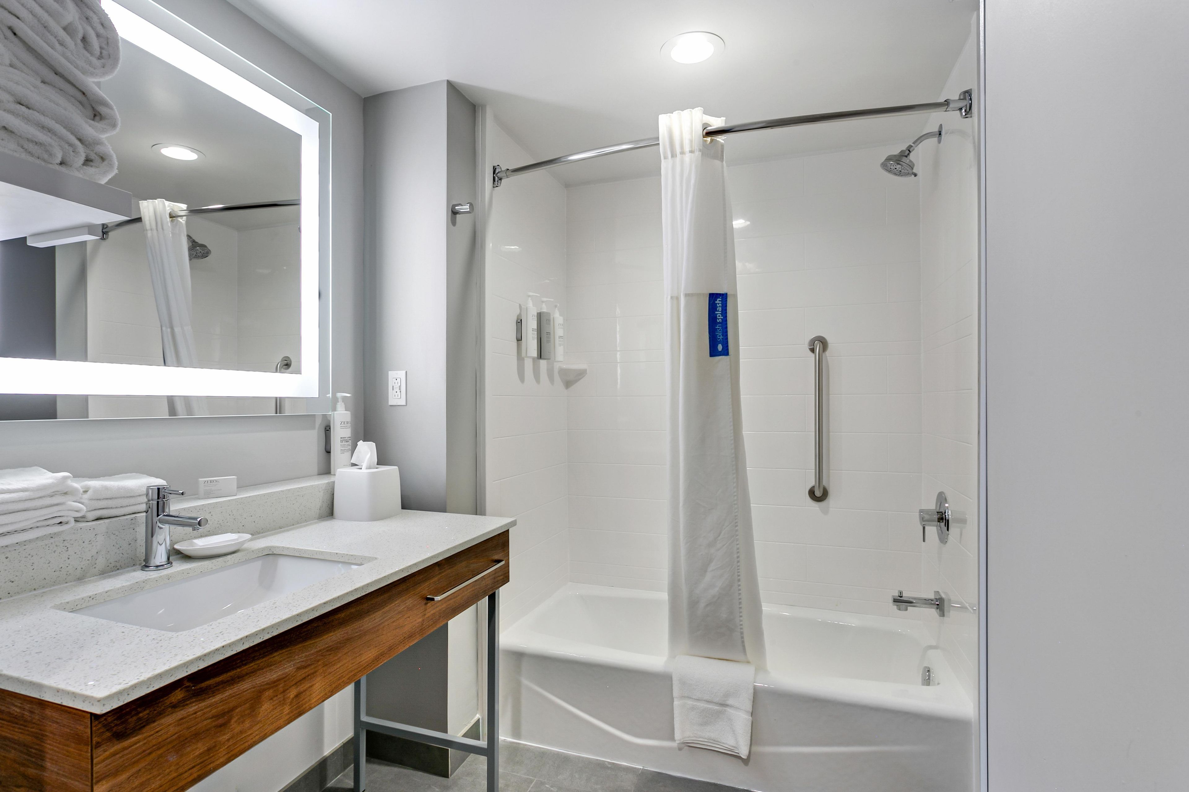 A modern bathroom with a glass-enclosed shower, a vanity with a sink, and a mirror.