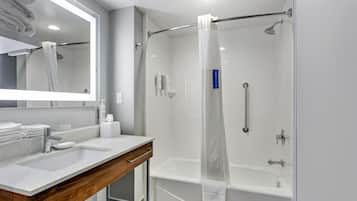 A modern bathroom with a glass-enclosed shower, a vanity with a sink, and a mirror.