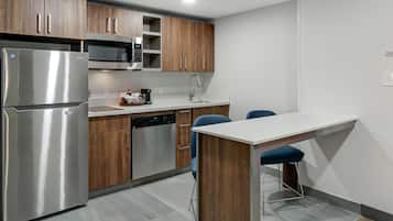 A modern kitchen with stainless steel appliances, wooden cabinets, and a white countertop.