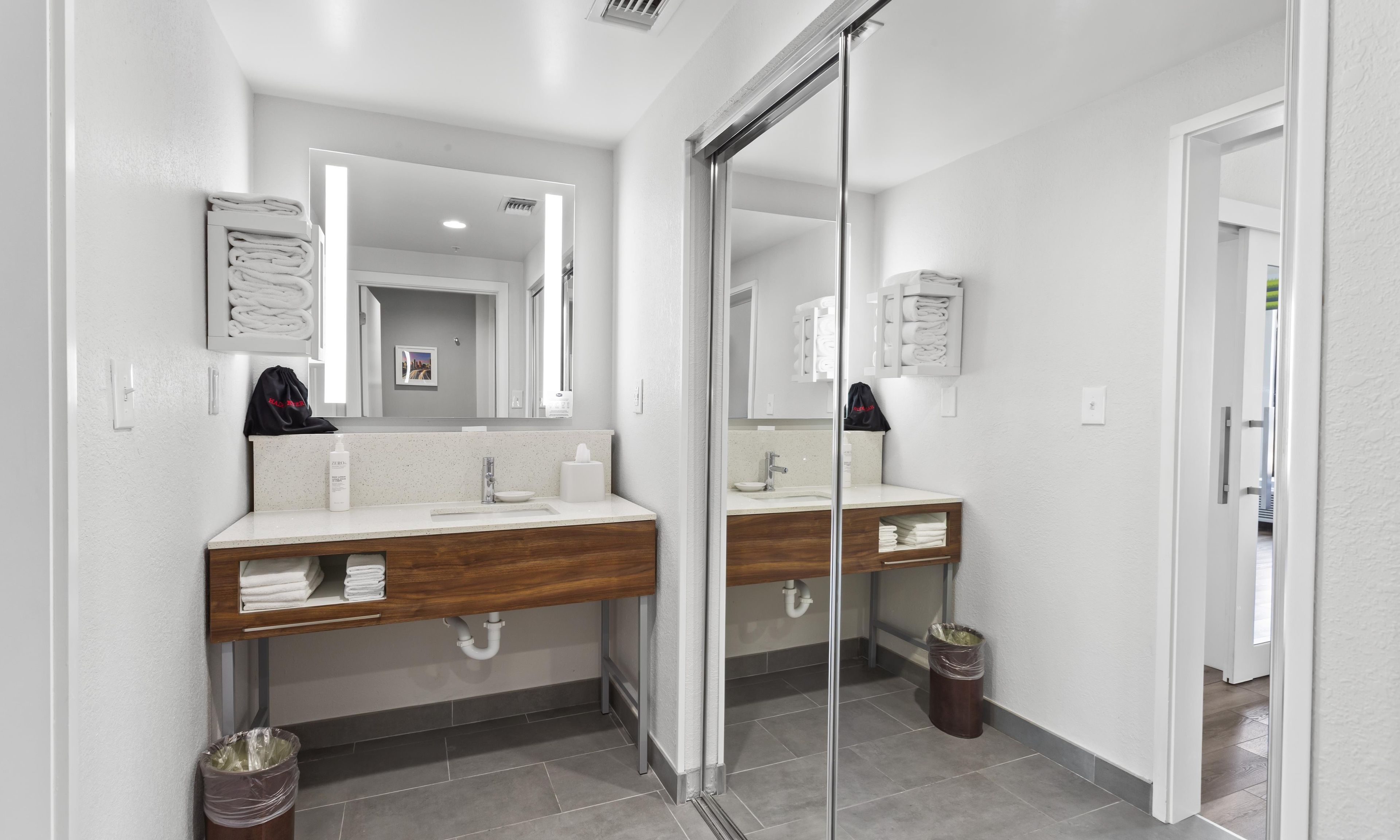 A modern bathroom with two sinks, a large mirror, and a glass shower door.
