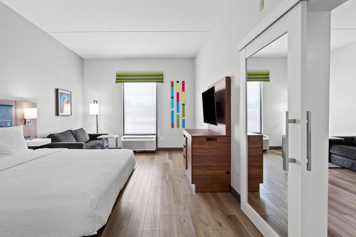 A hotel room with a bed, a desk, a TV, and a wardrobe.