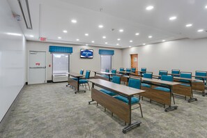 Un salón de conferencias con varias mesas y sillas, una señal de salida y un letrero de Hampton Inn.