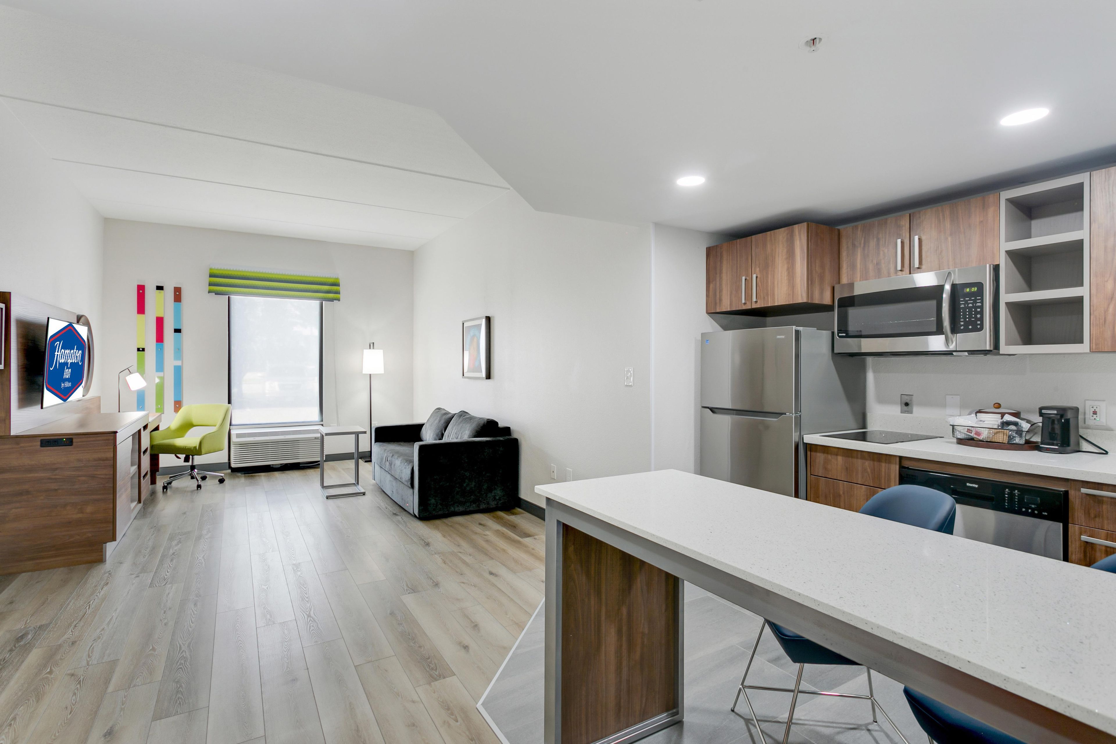 A modern kitchen with stainless steel appliances, a bar area, and a seating space with a sofa and chairs.