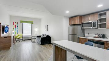A modern kitchen with stainless steel appliances, a bar area, and a seating space with a sofa and chairs.