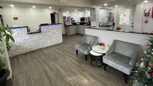 A modern hotel lobby with a reception desk, seating area, and a kitchenette. - Smoky View Inn (Pigeon Forge)