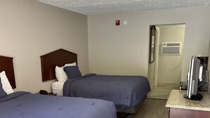 A hotel room with two beds, a desk with a computer, an air conditioning unit, and a door leading to another room. - Smoky View Inn (Pigeon Forge)