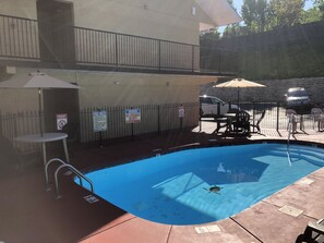 Une piscine avec un poste de surveillance pour le sauveteur et une table de billard avec des chaises.