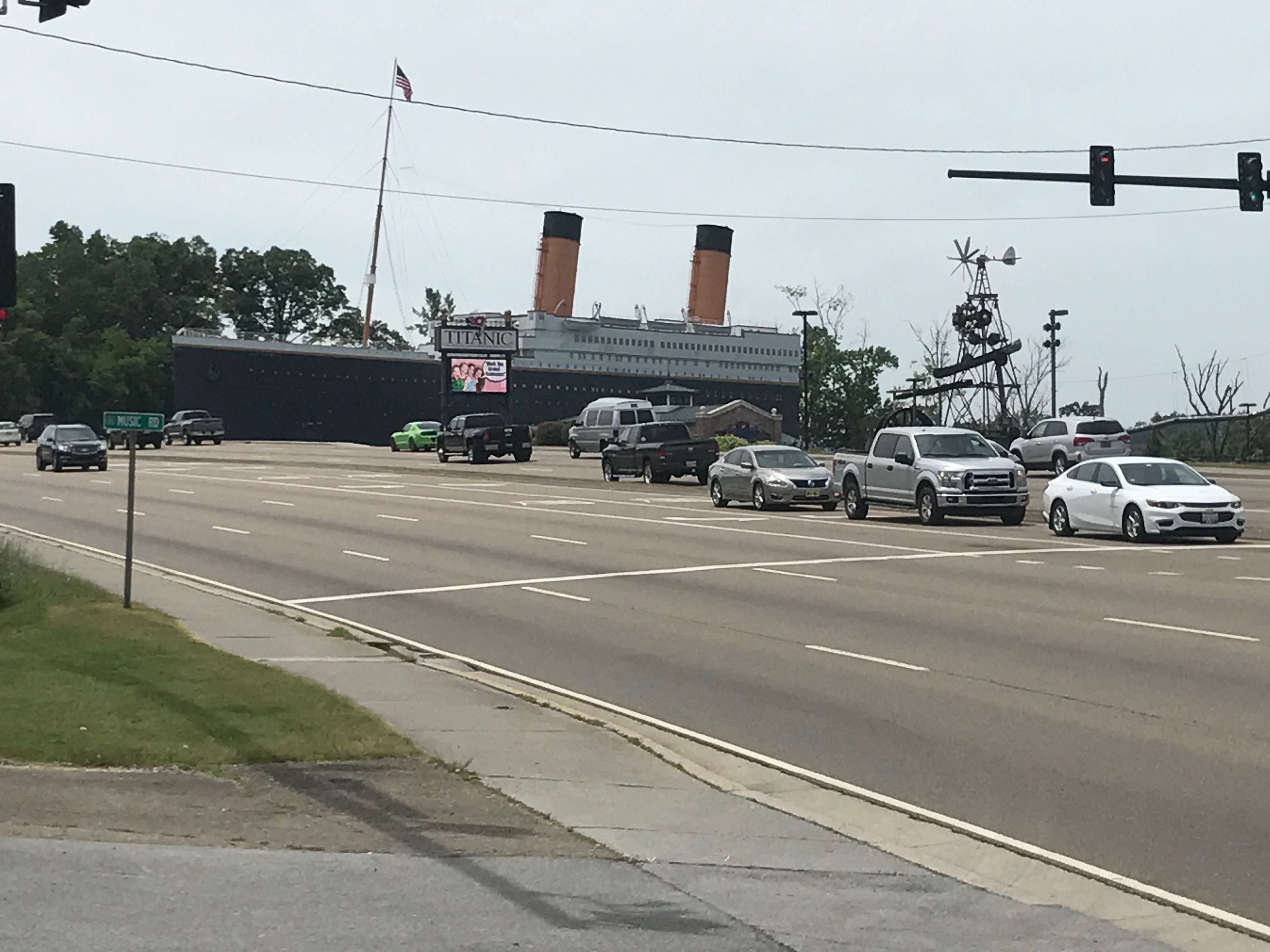 A highway with multiple lanes and vehicles, including cars and trucks. There is a large building with two chimneys and a sign that reads "TITANIC."