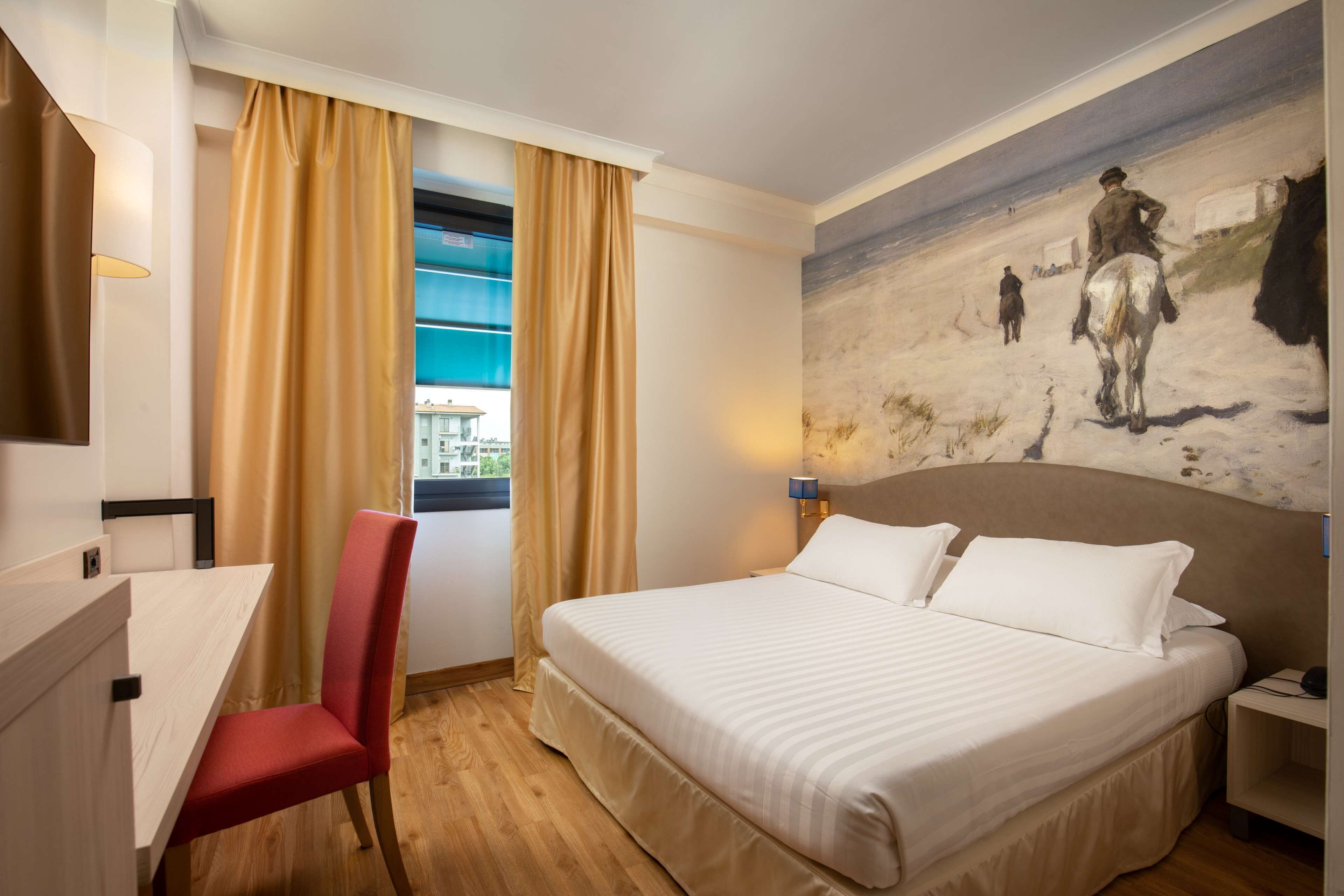 Une chambre d’hôtel avec un lit, un bureau, une chaise et un tableau au mur.