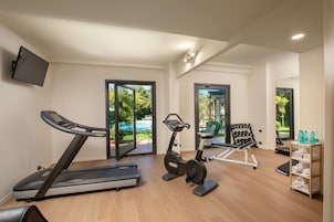 Un gimnasio en casa con cinta de correr, elíptica y banco de pesas.