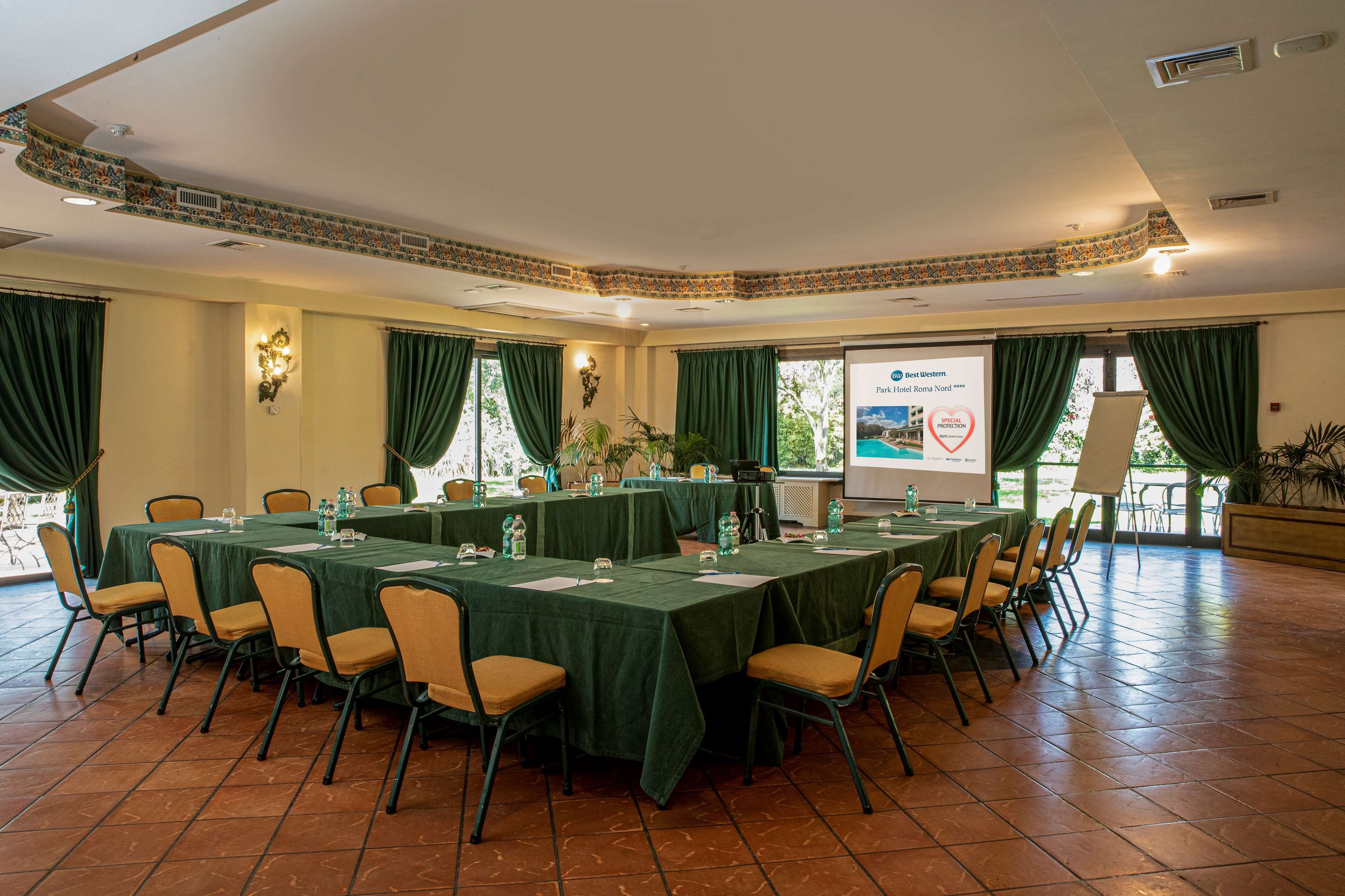 Una sala conferenze con un lungo tavolo, sedie e uno schermo per presentazioni.
