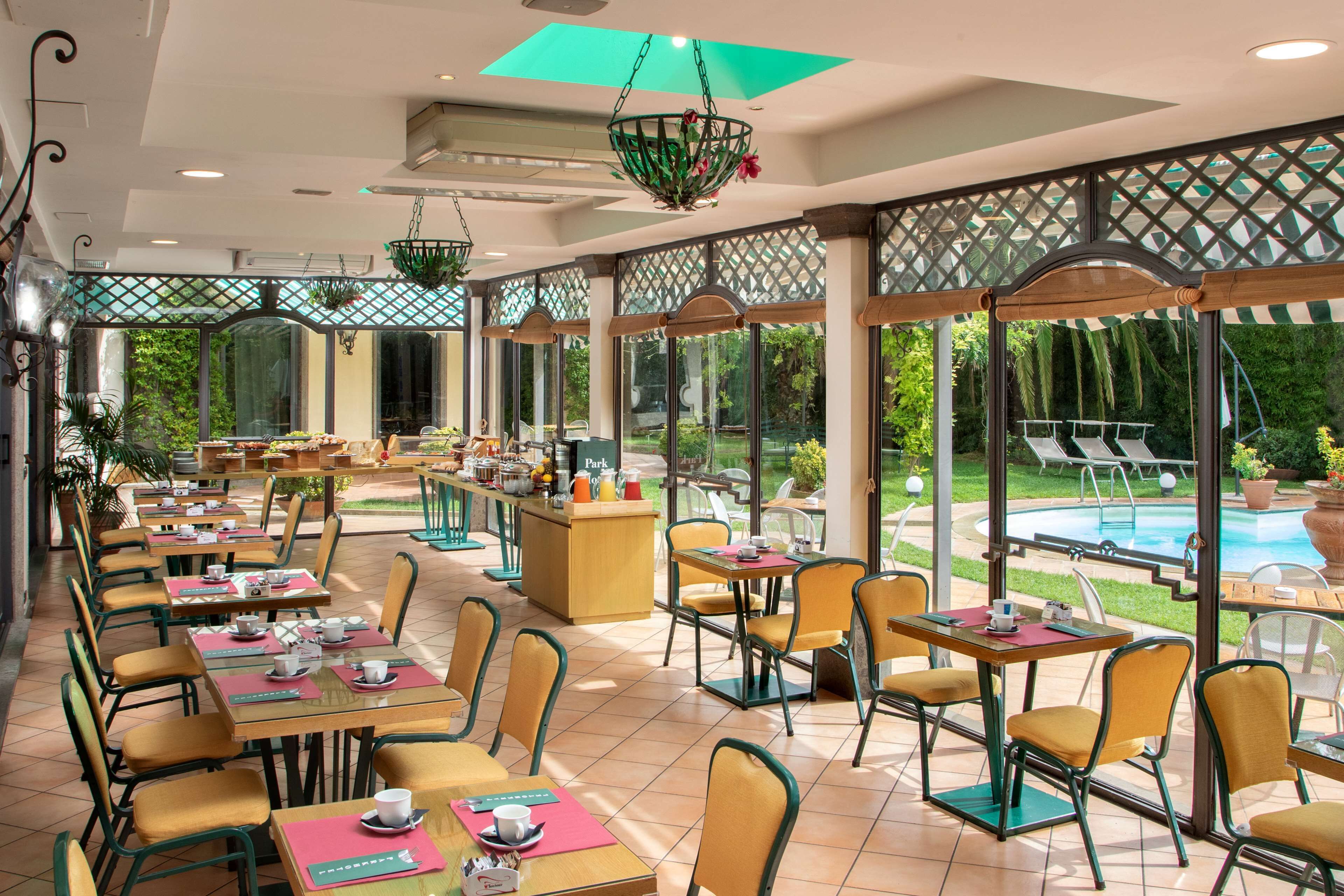 Un restaurante con terraza, piscina y vistas al paisaje verde.