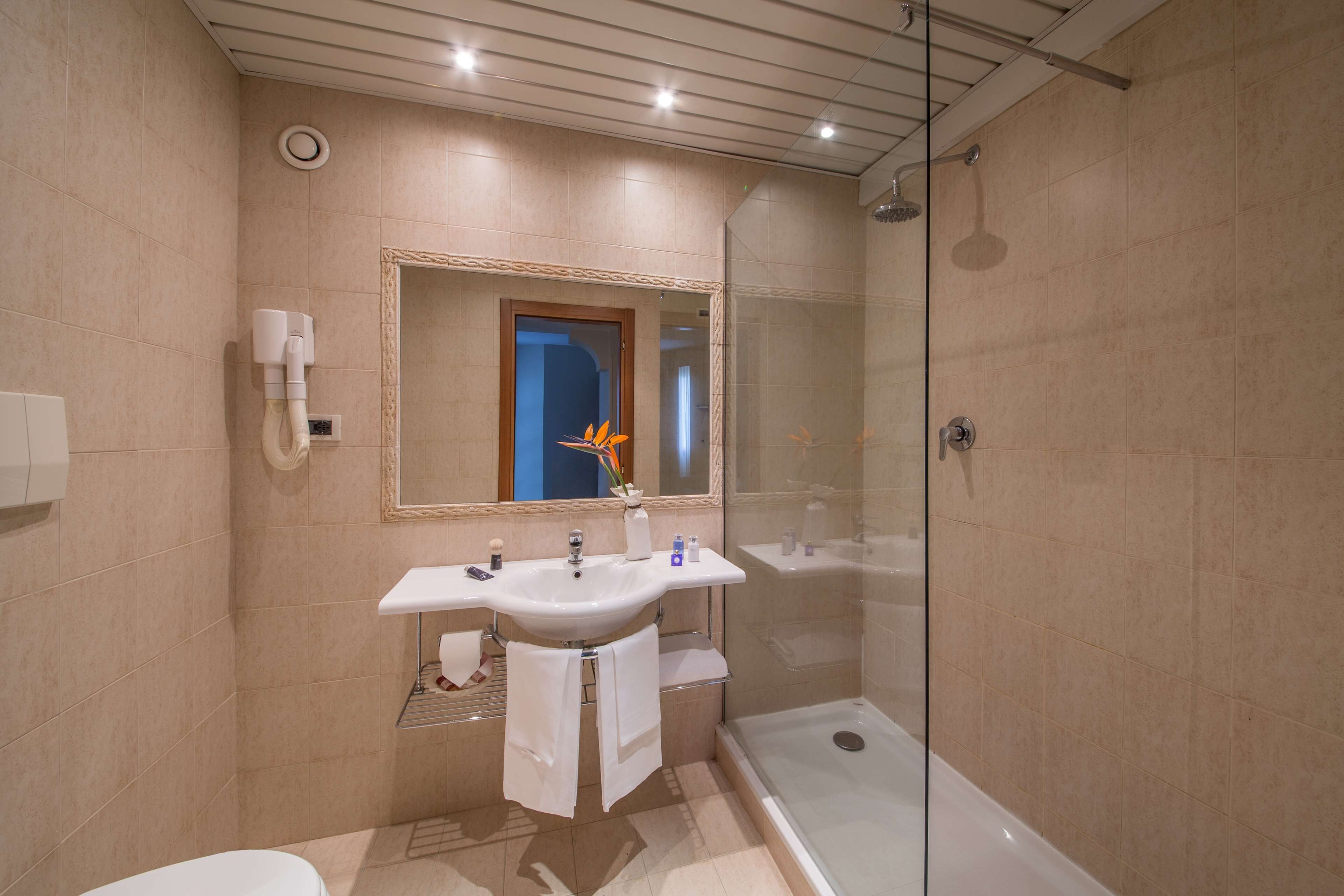A modern bathroom with a glass-enclosed shower, a double sink vanity, and a large mirror.
