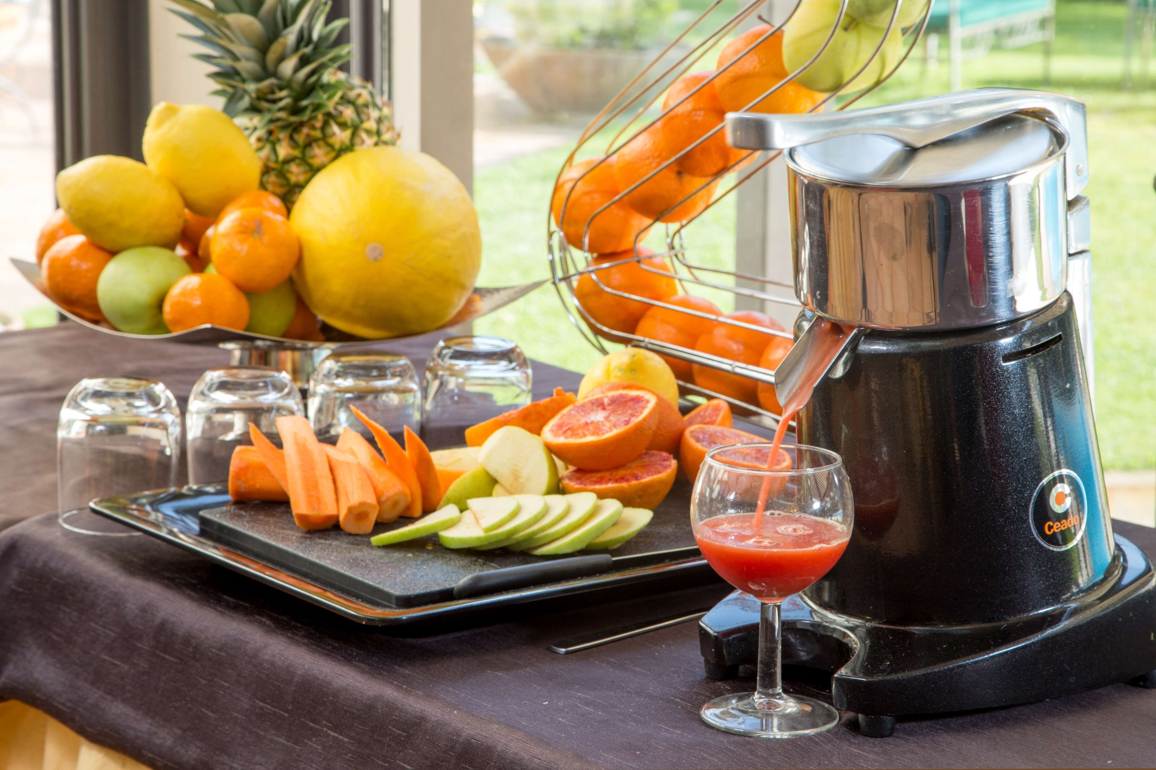 A juicer with a tray of sliced fruits and a glass of juice.