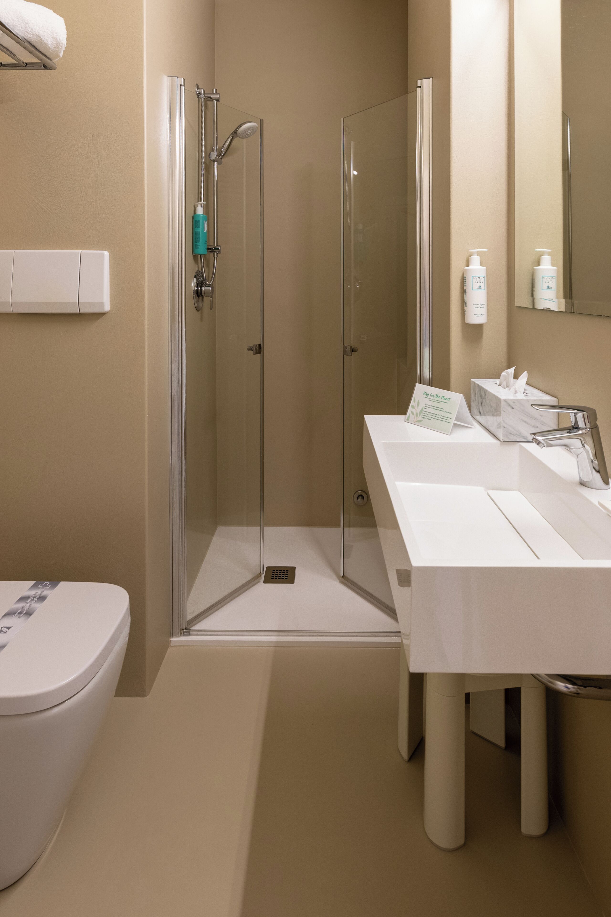 Un baño moderno con ducha de vidrio, lavamanos blanco y retrete.
