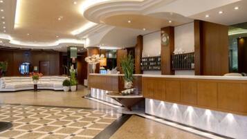 Un hall de hotel con mostrador de recepción, zona de estar y un mostrador de registro.