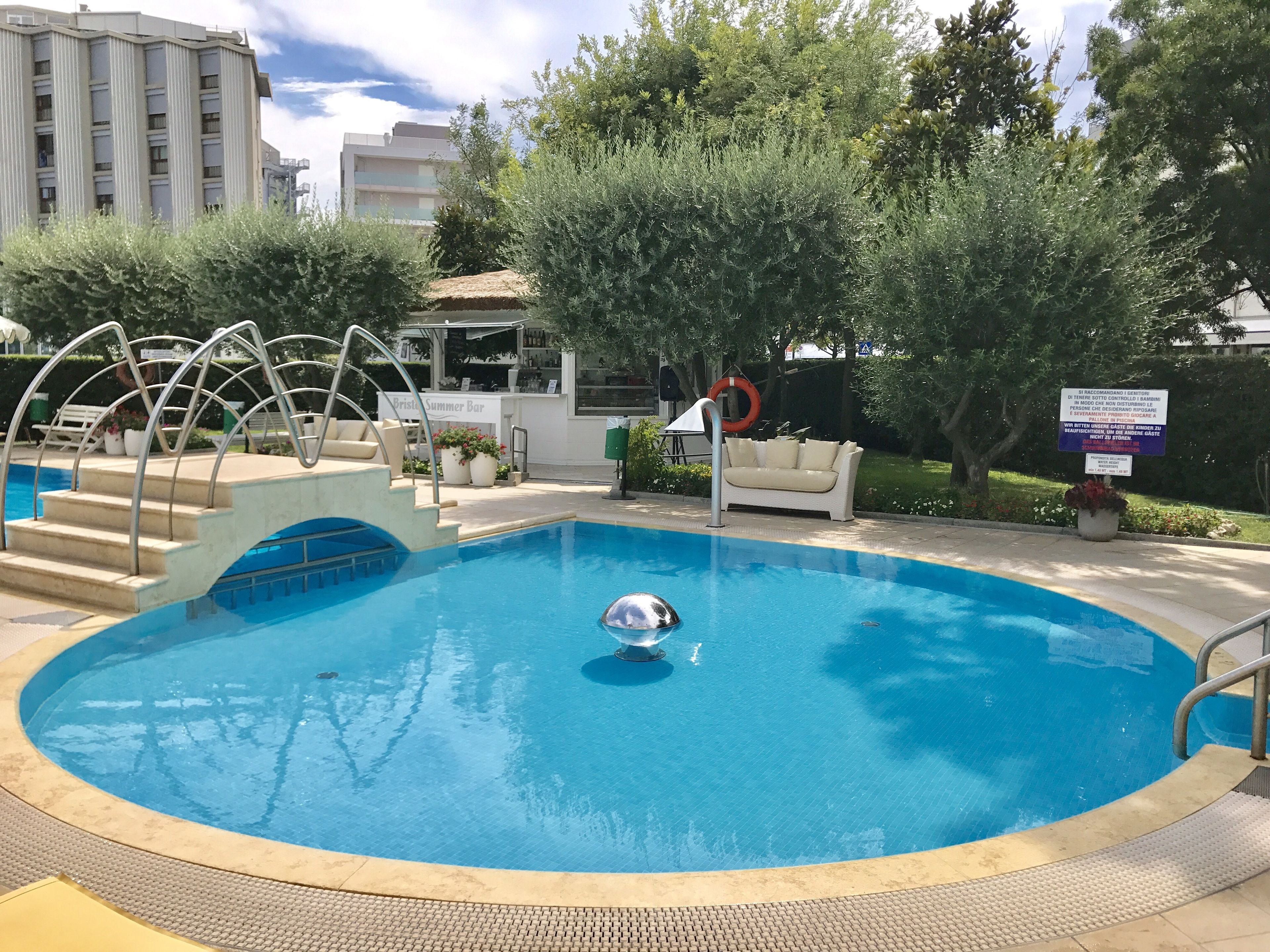 Una piscina con trampolín, un flotador salvavidas y un cartel.