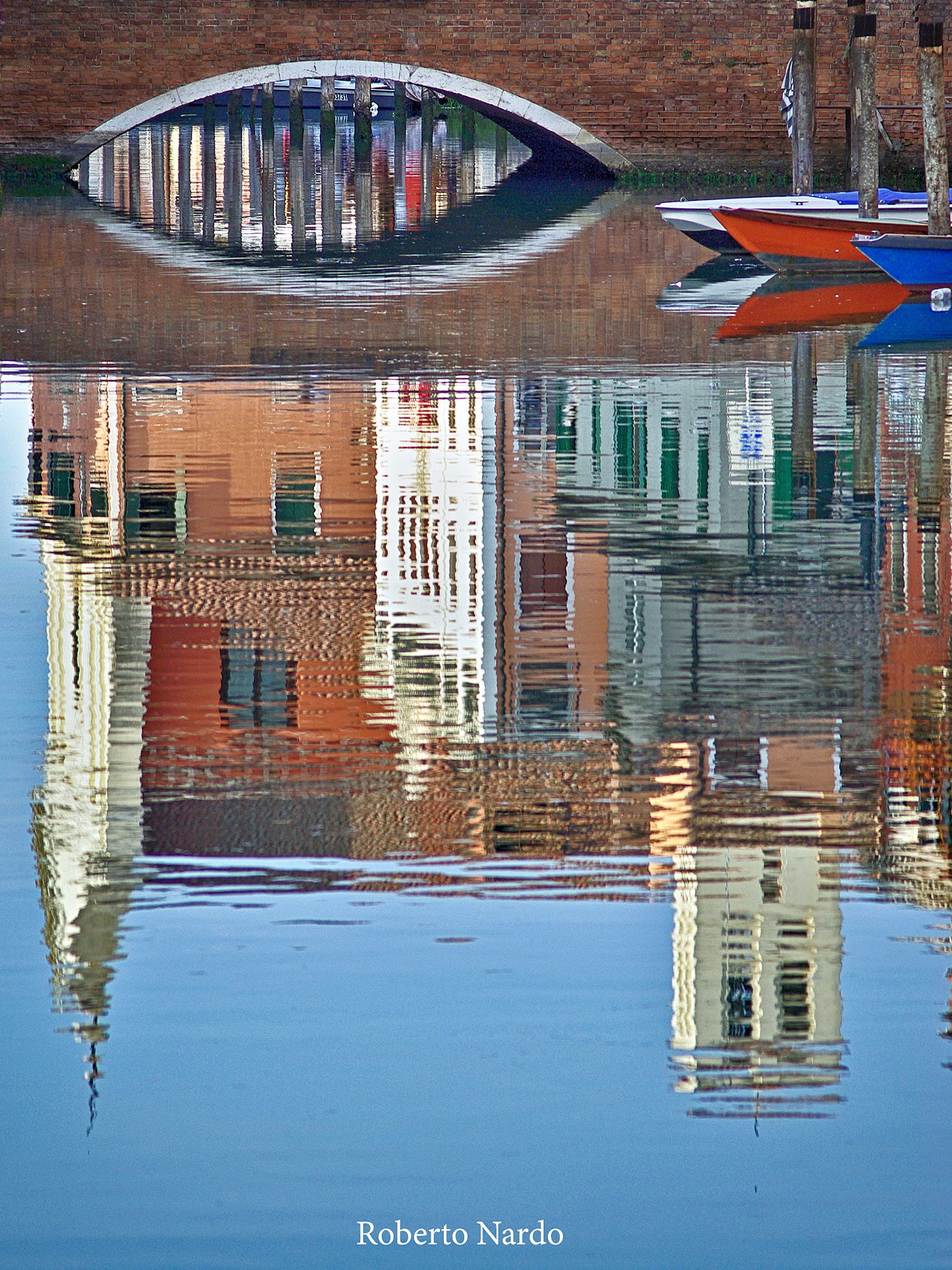 Una masa de agua tranquila que refleja un puente y barcos.