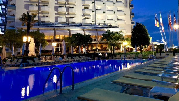 A hotel with a pool area, multiple balconies, and flags. - Hotel Bristol (Chioggia)