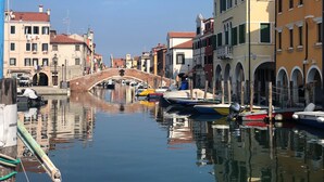 A canal with a bridge, boats, and buildings along the water. - Hotel Bristol (Chioggia)