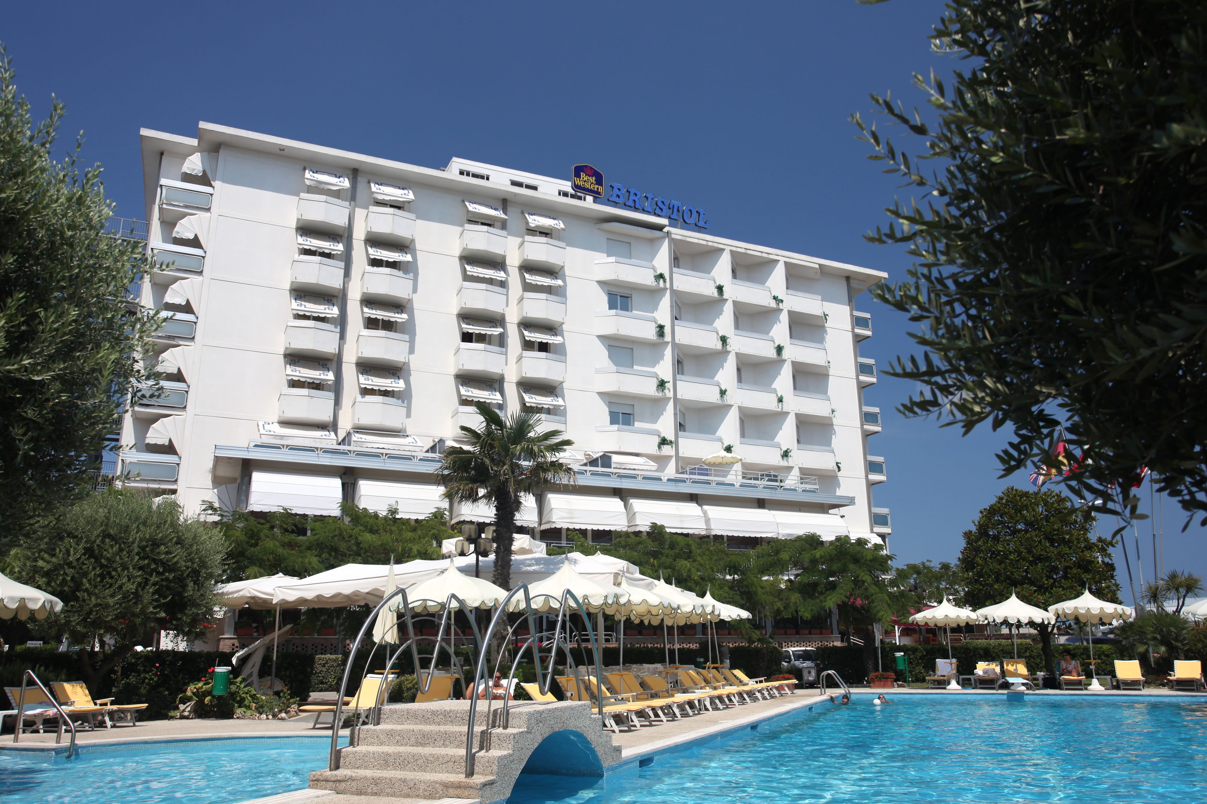 Um hotel com área de piscina, espreguiçadeiras e guarda-sóis.