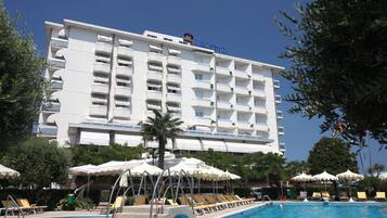 Ein Hotel mit Poolbereich, Liegestühlen und Sonnenschirmen.