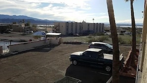 Ein Parkplatz mit zwei Autos, ein Gebäude mit flachem Dach und Berge im Hintergrund.
