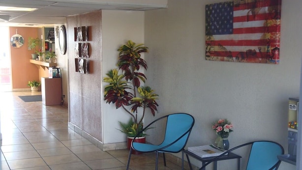 Ein Flur mit zwei blauen Stühlen, einem Topfpflanzen und einer amerikanischen Flagge an der Wand.