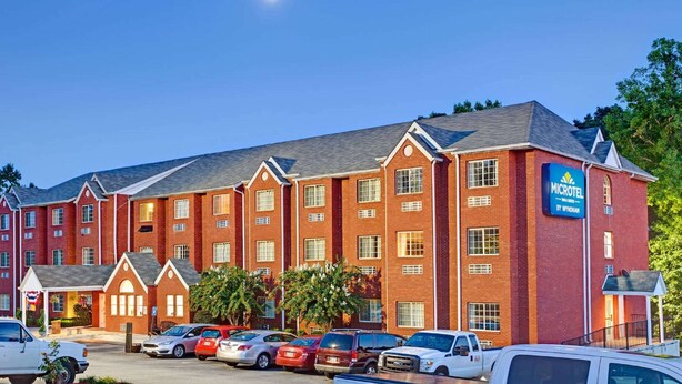 Ett Microtel Inn-hotell som tillhör Wyndham-kedjan, med en fasad av tegel, många fönster och en parkeringsplats med flera bilar.