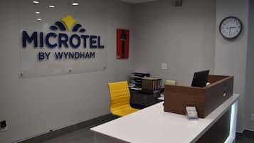 A reception desk with a sign reading "MICROTEL BY WYNDHAM," a clock, and a yellow chair.