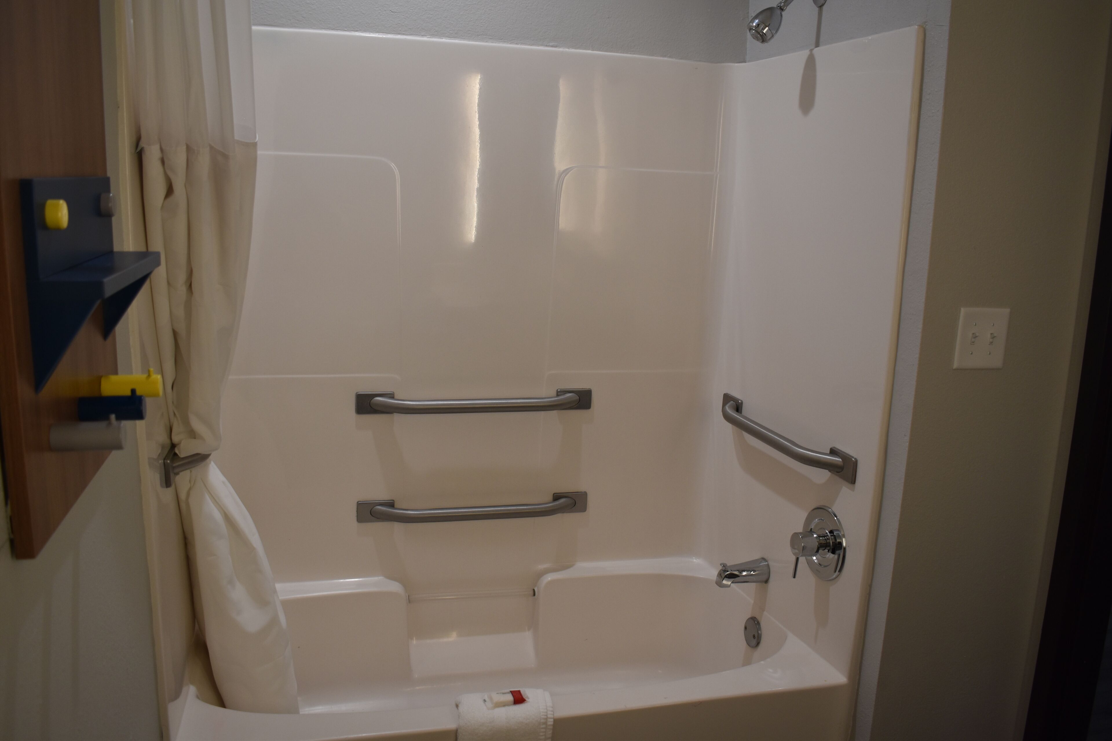 A bathroom with a bathtub, shower, and grab bars.