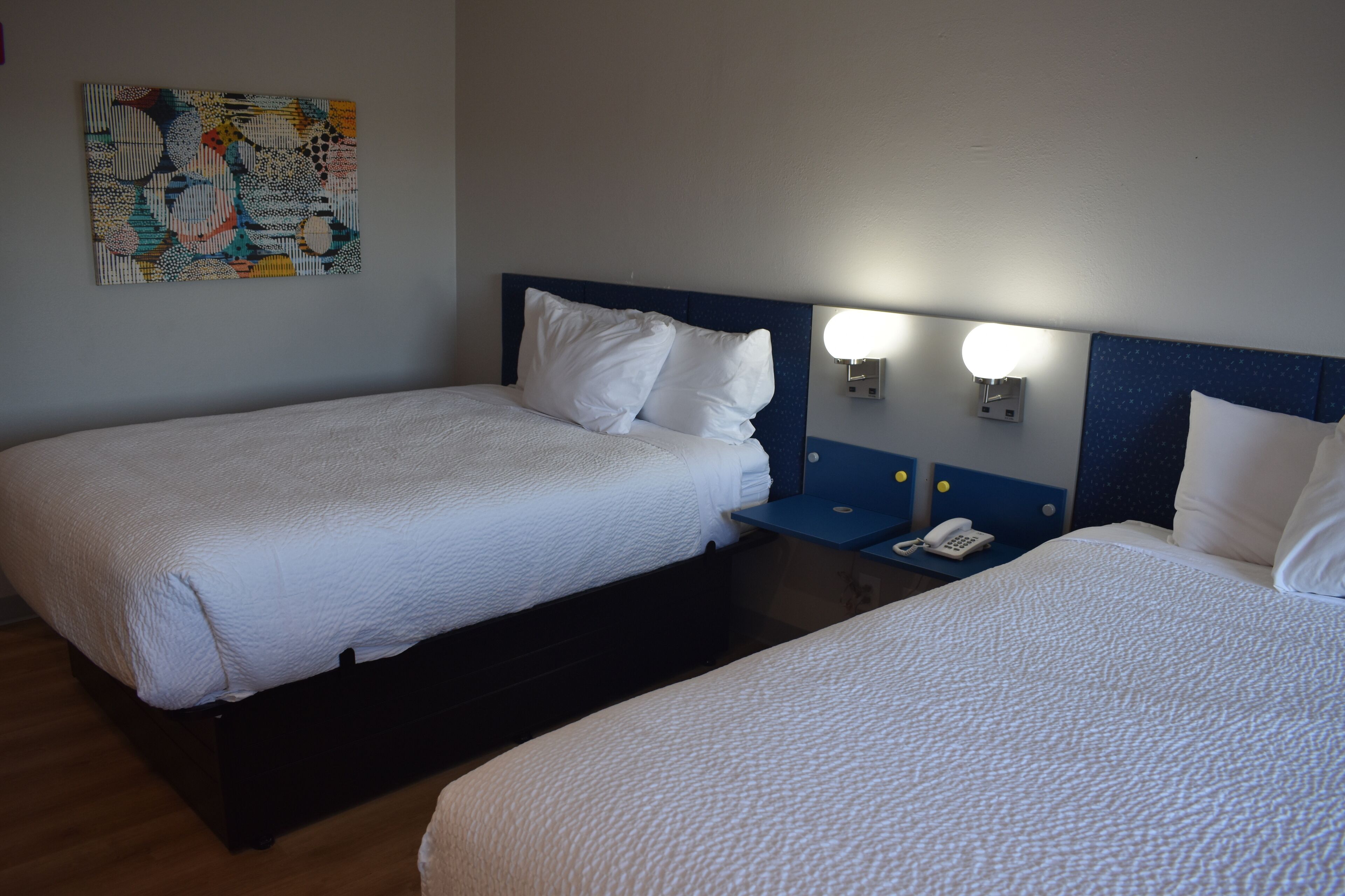 Ein Hotelzimmer mit zwei Einzelbetten, einem Nachttisch mit Telefon und einer Wandleuchte.