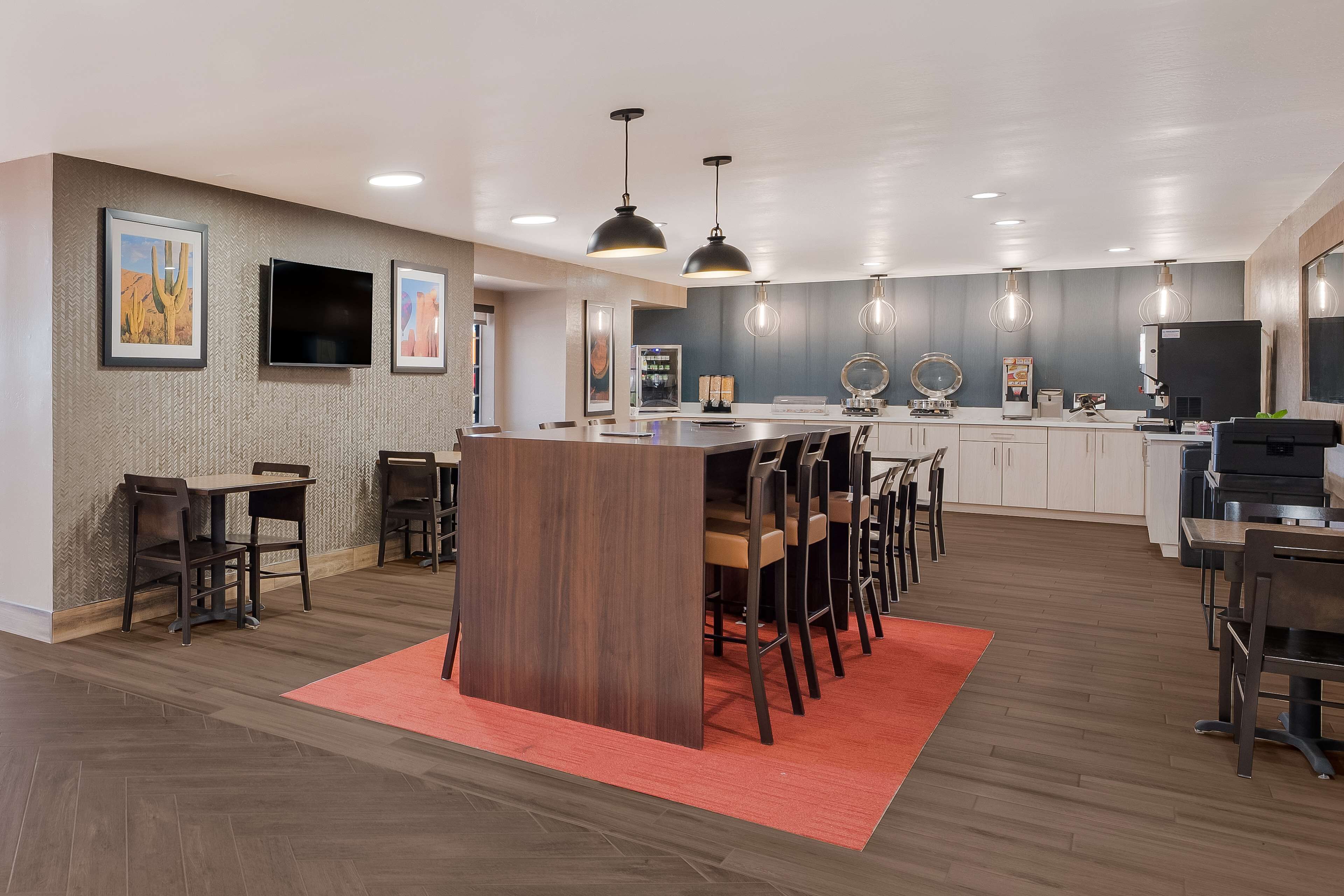 A modern kitchen with a central island, pendant lighting, and a herringbone wood floor.