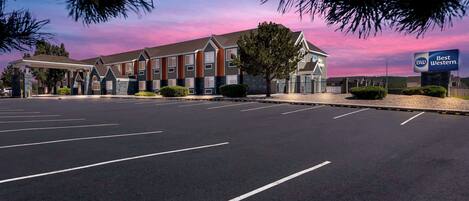 Um hotel Best Western com design arquitetônico moderno, com área de estacionamento coberta e paisagismo bem cuidado.