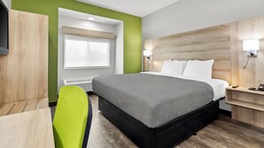 A modern hotel room with a large bed, a desk, and a chair. - Quality Inn Shallotte near Ocean Isle Beach (Shallotte)