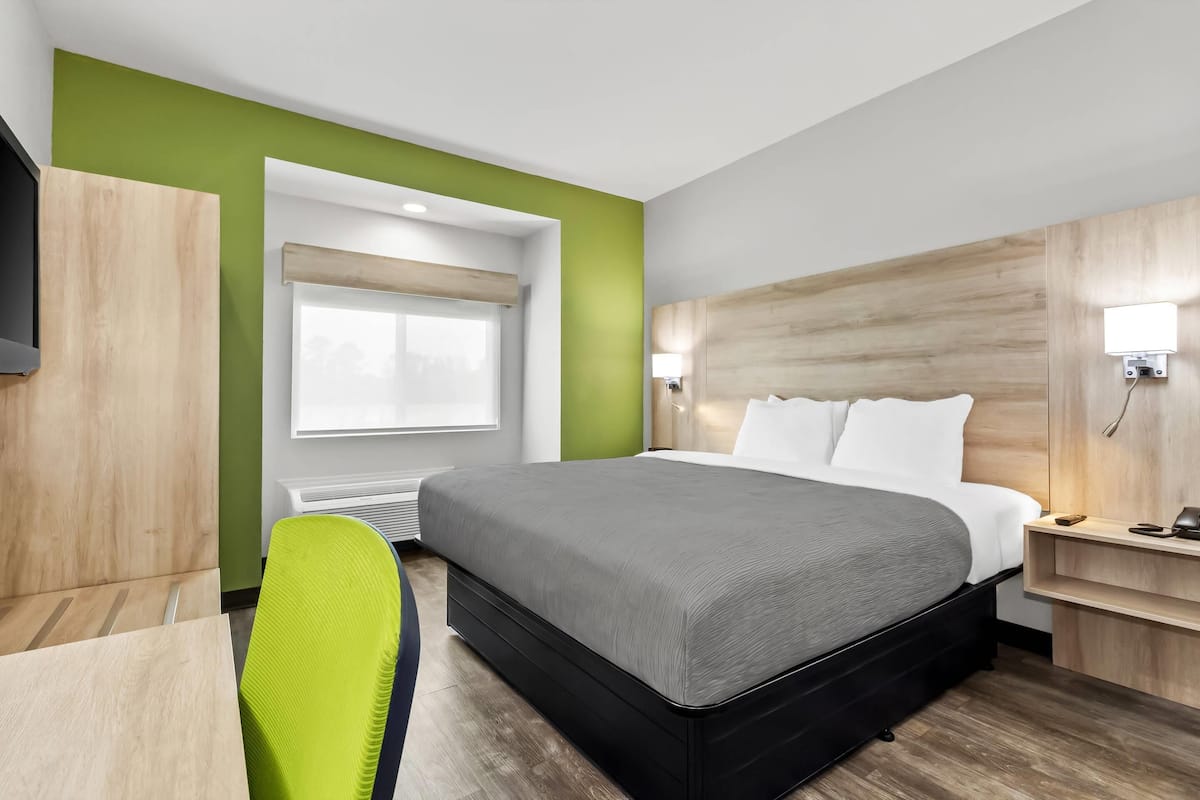 Ein modernes Hotelzimmer mit einem großen Bett, einem Schreibtisch und einem Sessel.