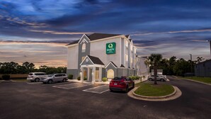 A hotel with a 'Quality Inn' sign, a parking lot with several cars, and a well-maintained lawn area. - Quality Inn Shallotte near Ocean Isle Beach (Shallotte)