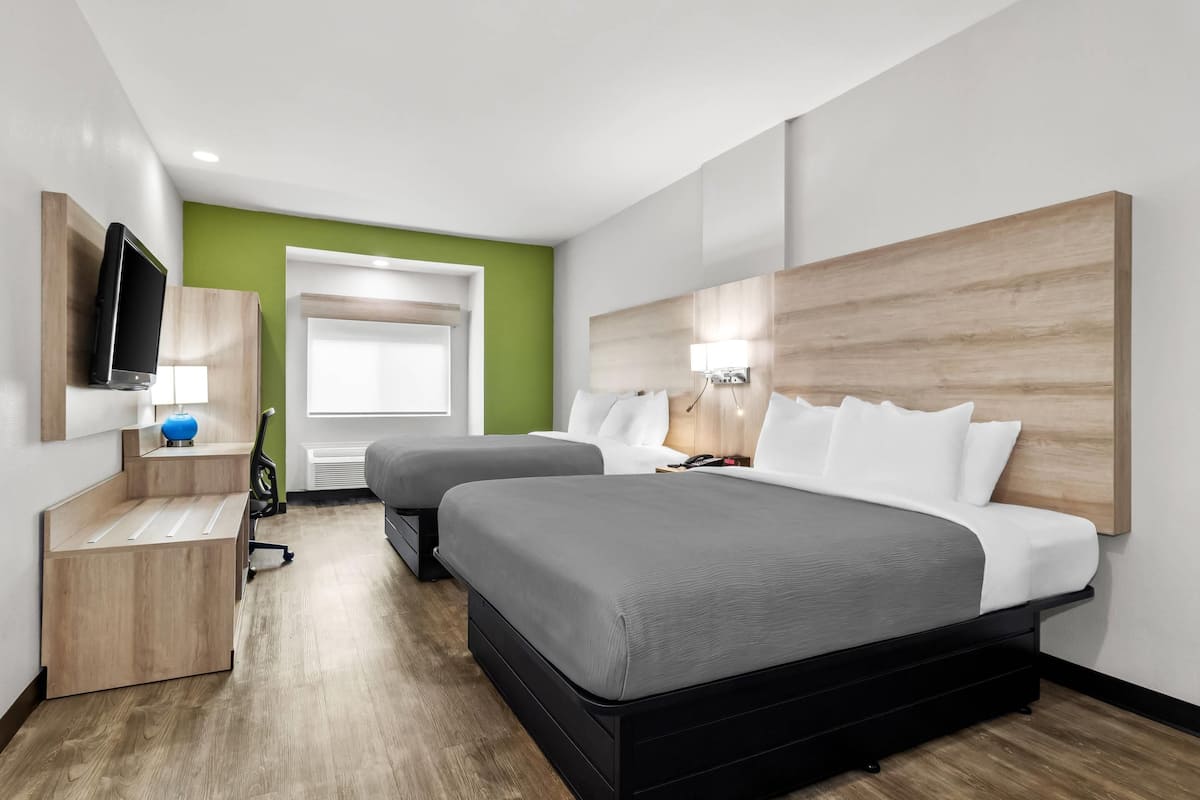 Ein modernes Hotelzimmer mit einem großen Bett, einem Schreibtisch, einem Fernseher und einer Wand in Grünton.