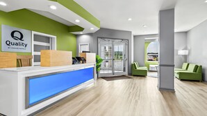 A hotel reception area with a modern design, featuring a reception desk, green and white walls, and a view of the outside. - Quality Inn Shallotte near Ocean Isle Beach (Shallotte)