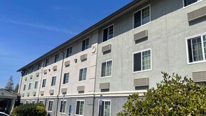 A multi-story building with a flat facade, multiple windows, and air conditioning units. - Super 8 by Wyndham Sacramento/Florin Rd (Sacramento)