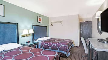 Une chambre d’hôtel avec deux lits, un bureau, une chaise, une télévision et une salle de bain équipée d’un porte-serviettes.
